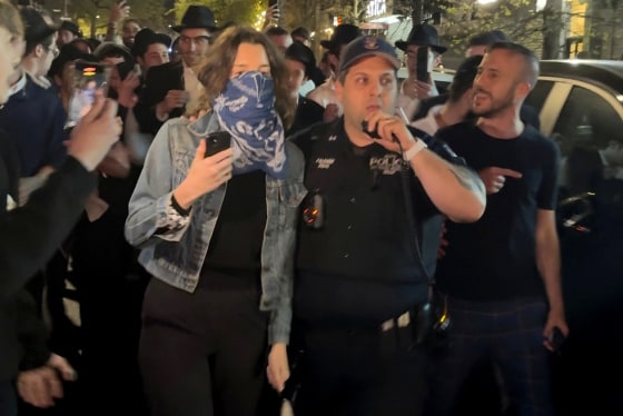 This image taken from video shows a woman and a police officer as they are pursued by a mob of Orthodox Jewish men