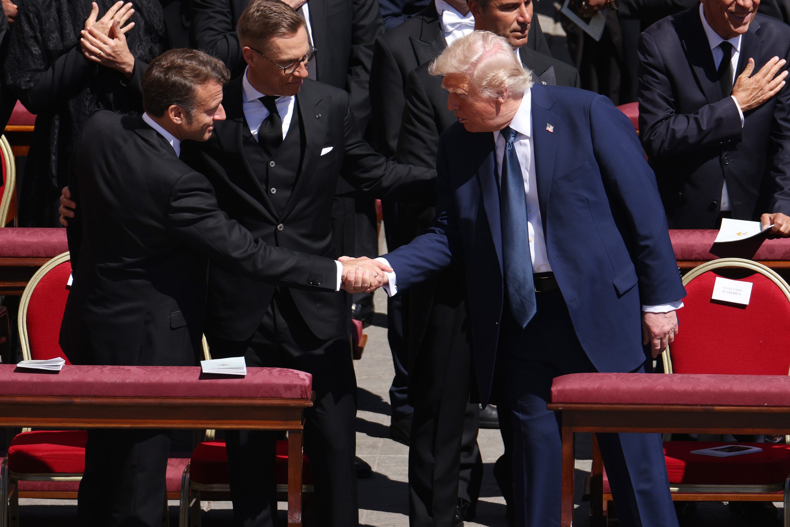 France's President Emmanuel Macron and US President Donald Trump shake heads while Finland President Alexander Stubb stands between them | Source: Getty Images