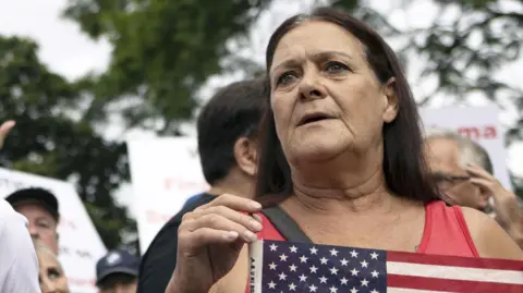 EPA A female protester who supports Donald Trump's refugee plan in South Africa holding an American flag.